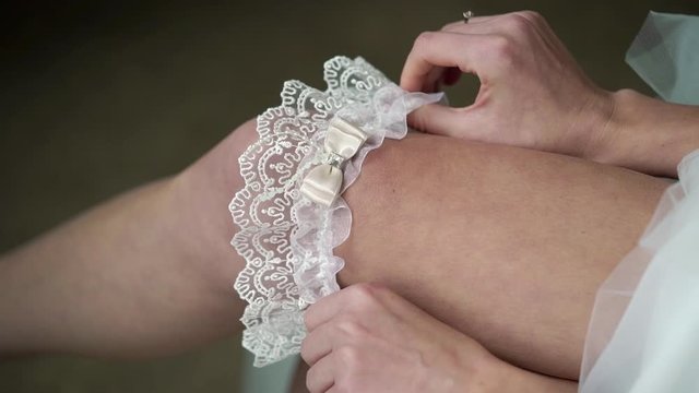 Young bride put on garter on her leg. Wedding