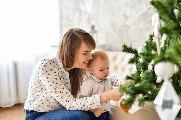 Christmas and new year. Mother and son sitting at the Christmas tree and consider toys. Horizontal...