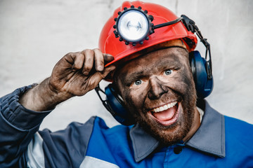 Portrait happy male miner after working in coal mine, dirty face in helmet