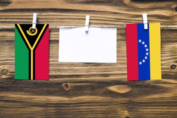 Hanging flags of Vanuatu and Venezuela attached to rope with clothes pins with copy space on white...