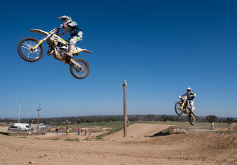 Motocross race bikers jumping and driffting on sand road