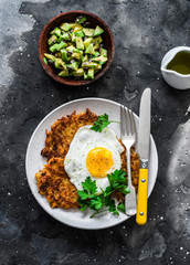 Sweet potato rostis with fried egg and avocado salsa on dark background, top view