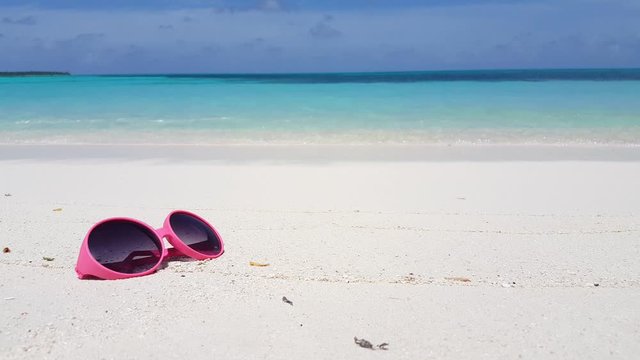 abstract summer vacation background. Close up of pink sunglasses on the white soft sand, tropical luxury vacation concept