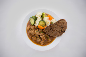 beef casserole in the bowl with steamed vegetable