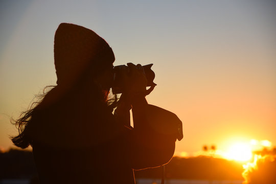 Silhouette of young woman taking a picture