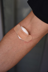 Male arm with band aid and cotton on blood draw site