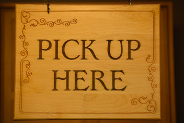 Wooden "Pick up here" sign. Close up.
