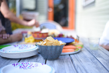 Pita chips in a small bowl and assorted foods blurry