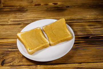 Two slices of bread with peanut butter on wooden table