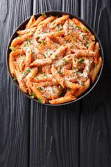Tasty traditional pasta alla vodka topped with parmesan and parsley close-up in a plate. Vertical...