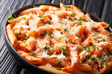 Tasty traditional pasta alla vodka topped with parmesan and parsley close-up in a plate. horizontal