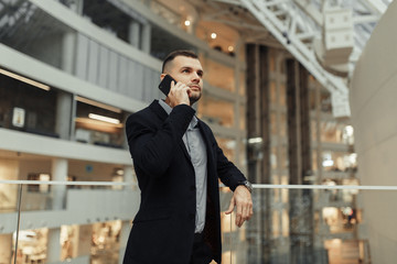 Conversations and phone calls, negotiations. Portrait of a young successful man in the office.