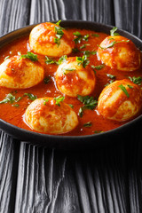 Boiled curry eggs in spicy sauce close-up in a plate. vertical