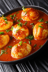 Indian traditional food curry eggs in spicy sauce close-up in a plate. vertical