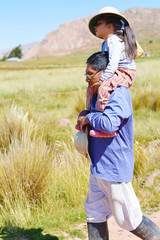 Native american man with his little daughter on shoulders in the countryside.