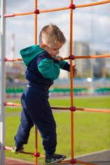 Obraz premium A little boy climbs the ropes on the Playground.