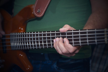 Fototapeta na wymiar electric bass guitar in male hands, dark background