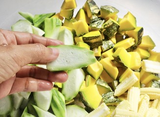 Hand Holding Chopped Sponge Gourds with Pumpkins and Baby Corns
