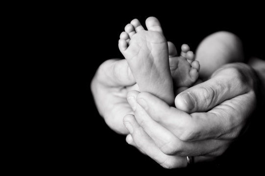 newborn baby feet in fathers hands