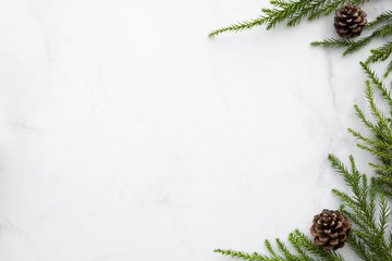White marble table with Christmas decoration including pine branches and pine cones. Merry...