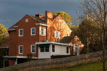 Old vintage red brick house shinning on sunlight during storm.