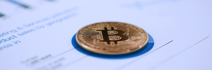 Golden btc sign coin lying at stats graph closeup
