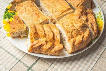 Slices of baked delicious pie with chicken and potatoes in plate on kitchen table.