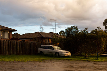 Obraz na płótnie Canvas Abandoned white car left behind houses in suburbia.