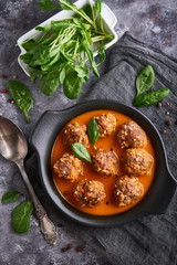 homemade meatballs with tomato sauce and spinach in a plate on a dark background Copyspace Top view