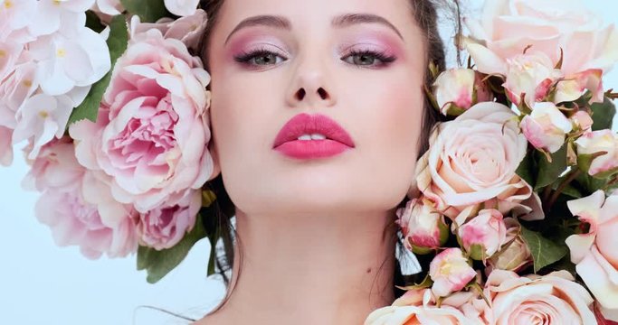 Face with flowers. Beautiful caucasian woman with fresh skin. Closeup female face with flowers. Beauty concept. Skin care. Young girl with natural makeup. 4k. Slow motion