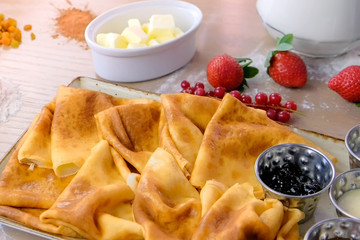 Traditional russian pancakes, blini. Served with jams, sour cream, milk and strawberry on the plate. Side view