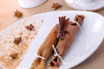 Chocolate russian pancakes, blini with curd filling on the plate. Close-up view