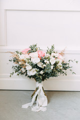 Floristry of eucalyptus and Ranunculus in the hands. The bride's bouquet in the bright Studio.
