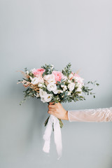 Floristry of eucalyptus and Ranunculus in the hands. The bride's bouquet in the bright Studio.