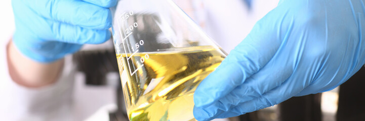 Male hands in protective gloves hold test tube