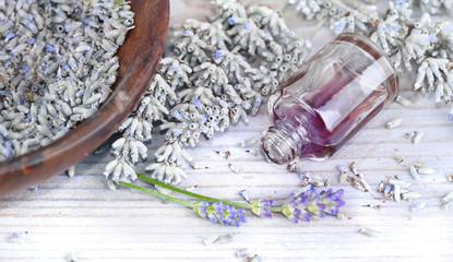 essential oil from lavender in a overturned bottle and dried flowers
