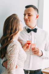 Stylish wedding in European style. Beautiful couple celebrating and drinking champagne in the Studio.