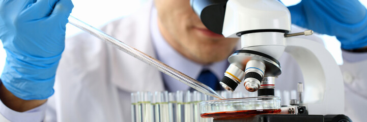 Portrait of a young chemist looking in binocular