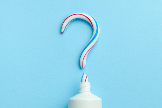Question mark from toothpaste. Concept of choosing good toothpaste for teeth whitening. Tube of colored toothpaste on blue background. Copy space for text.