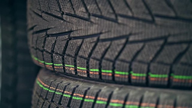 Many new winter tires on shelves and in columns. New winter tires close up.