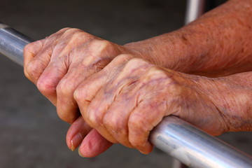 close up old woman hands,she sitting on chair and holding the walker by two hands.