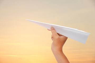 paper plane in hand on the sky background.