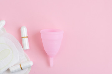 pink menstrual Cup, tampons, pads on pink background. woman period concept.