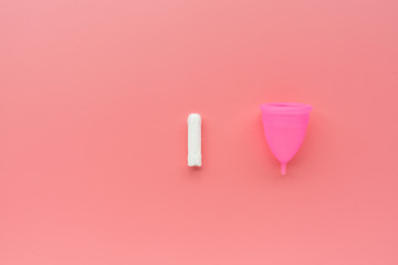 Menstrual cup and tampon on pink background. Alternative feminine hygiene product during the period. Women health concept. Copy space. Eco friendly concept, zero waste product. Flat lay, mockup