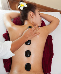 beautiful young woman lying on bed  spa and on her back is  hot stone for treatment healthy. - 300080882