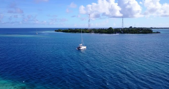 Boat Approaching Tropical Island, luxury vacation concept, aerial orbiting shot