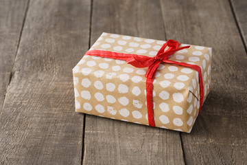 Paper wrapped gift box decorated with red bow and ribbon.