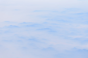 The mountains has covered by cloudy in sunrise time, view from window on the plane.