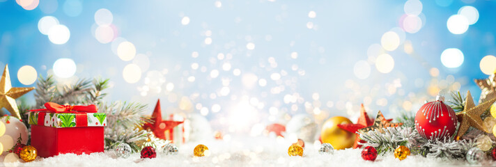 Christmas winter background with gift box, Christmas baubles and fir tree branches on snow.