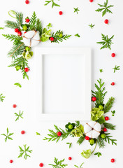 Christmas composition  with photo frame, cotton flower, branches of spruce and holly with red berries on white background. Merry christmas greeting card with empty space for holiday text.